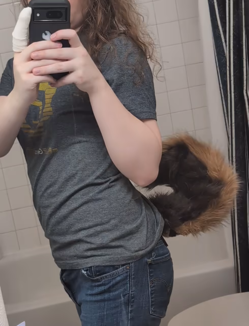 Julia wearing her little husky tail wagging in the mirror. Her hand is bandaged up.